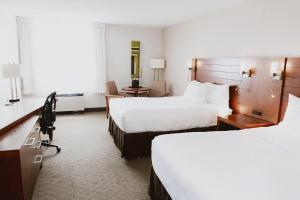 a hotel room with two beds and a desk at Quality Inn Rouyn-Noranda in Rouyn-Noranda