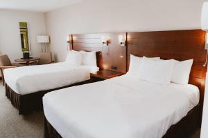 two beds in a hotel room with white sheets at Quality Inn Rouyn-Noranda in Rouyn-Noranda