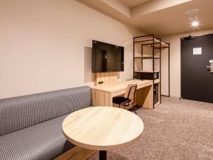 a room with a couch and a desk and a television at Comfort Hotel Takamatsu in Takamatsu