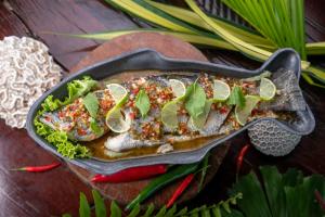 a pan of fish with sauce and vegetables on a table at One Beach Resort by EHM in Koh Rong Sanloem