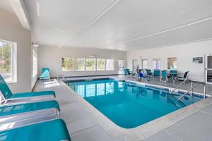 a swimming pool with blue chairs and tables at Comfort Inn & Suites Harrisburg-Hershey North in Manor Acres