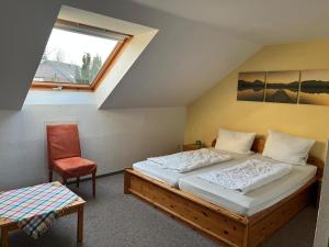a bedroom with a bed and a chair and a window at Haus Panorama Sankt Andreasberg in Sankt Andreasberg