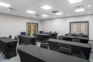 an empty room with black tables and chairs at Country Inn & Suites by Radisson, Jacksonville West, FL in Jacksonville +76 photos