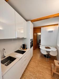 a kitchen with white cabinets and a sink and a table at Rooftop Teatro Aveiro in Aveiro