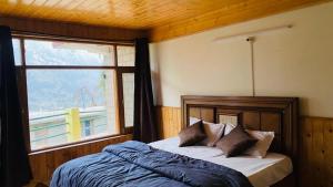 a bedroom with a bed with a window at Hotel sno cottage in Vashisht