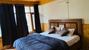 a bedroom with a bed with black curtains and a window at Hotel sno cottage in Vashisht