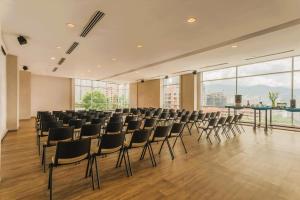 an empty room with chairs and tables and windows at V Grand Hotel, a member of Radisson Individuals in Medellín