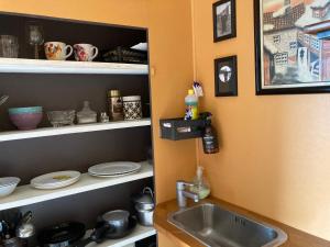 a kitchen with a sink and a shelf with dishes at Hen Stasjon Banevokterboligen in Hen