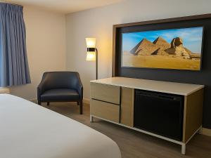 a hotel room with a tv and a chair at Rancho San Diego Inn & Suites in El Cajon