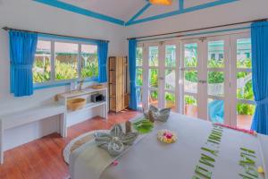 a living room with a white table and blue curtains at Casa Kapuas in Gili Trawangan