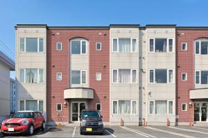 aartment building with two cars parked in a parking lot at STAY IN PASSION in Asahikawa