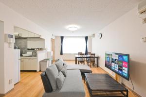a living room with a couch and a flat screen tv at STAY IN PASSION in Asahikawa