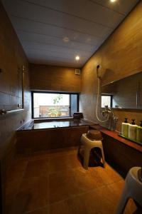 a large bathroom with a tub and a stool in it at Oyado Iseya in Shiojiri
