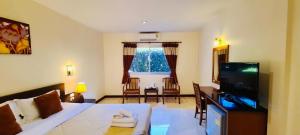 un dormitorio con cama y una sala de estar con televisión en Prachuap Place Hotel, en Prachuap Khiri Khan