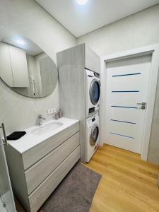 a bathroom with a sink and a washing machine at Apartamentai parke, su vaizdu į upę - Šešupės terasos in Marijampolė +9 photos