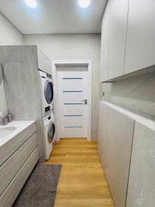 a kitchen with a washing machine and a white door at Apartamentai parke, su vaizdu į upę - Šešupės terasos in Marijampolė