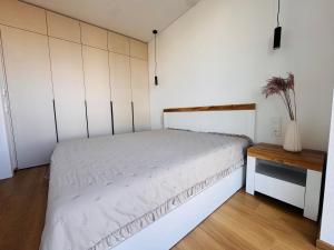 a bedroom with a white bed and a table at Apartamentai parke, su vaizdu į upę - Šešupės terasos in Marijampolė