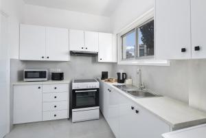 a white kitchen with white cabinets and a sink at Urban Condo Promitheos in Nicosia