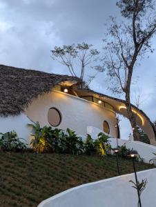 a large white building with a thatched roof at Earth's Embrace in Kalpetta