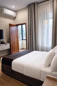 a bedroom with a large white bed and a window at Magnolia Suites B&B in Dar es Salaam +25 photos