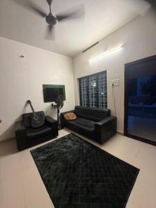 a living room with a black couch and a tv at Villa Mud Apple in Varkala