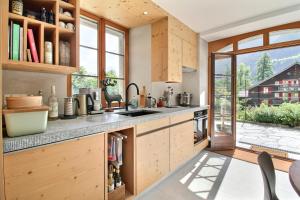 a kitchen with wooden cabinets and a large window at Garden Heart of the village Swedish Stove in Champéry