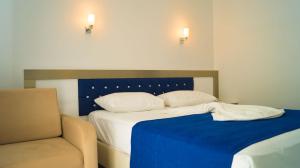 a bedroom with a bed with a blue blanket and a chair at Taşucu Kaptan Suit Otel in Silifke