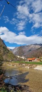 a river with a house and mountains in the background at Green River Apartment in Stahovica