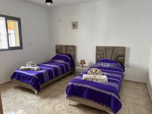 two beds in a room with purple sheets at Villa Al-Qamar in Midoun +11 photos