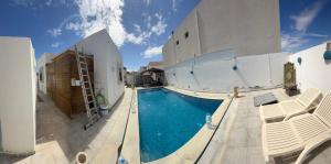 a swimming pool with chairs next to a building at Villa Al-Qamar in Midoun