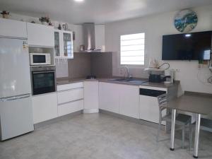 a kitchen with white cabinets and a sink and a table at Villa Madras in Sainte-Anne