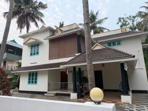 a house with palm trees in front of it at Villa Mud Apple in Varkala
