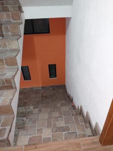 a room with an orange wall and a stone floor at Armonías 2 in Panajachel