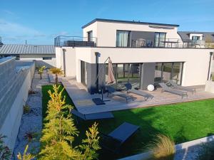 a house with a deck with chairs and an umbrella at Villa Ty Varcq in Locquirec