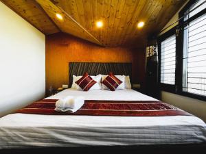 a bedroom with a large bed with red and white pillows at Nirvana Rooms - Shimla in Shimla