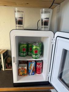 an open refrigerator with soda cans and food inside at Le meublé de belvédère in Belvédère