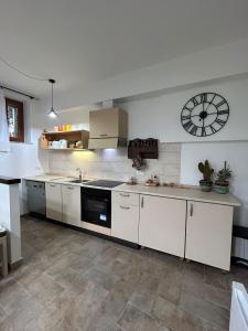 a kitchen with white cabinets and a clock on the wall at Costa Del Sole 48 in Camporsevoli