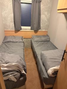 two beds in a small room with a window at sea view caravan park in Ingoldmells