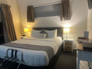 a bedroom with a large bed with white pillows at Two Tree Motel & Lodge in Blenheim
