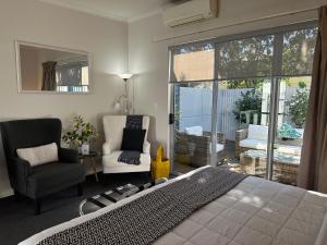 a bedroom with a bed and a chair and a window at Two Tree Motel & Lodge in Blenheim