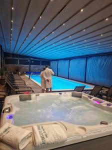 a man standing next to a large swimming pool at Thermae D'Olimpia & SPA in Băile Herculane