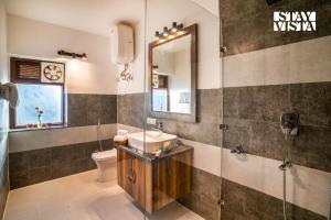a bathroom with a sink and a toilet and a mirror at StayVista at Cedar Crest Villa with Bonfire, Valley View in Kasauli +23 photos
