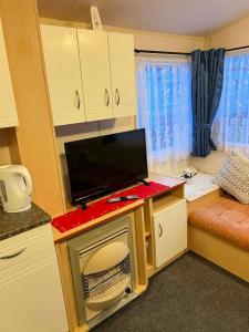 a small room with a desk with a tv on it at Seawick Beach Caravan in Saint Osyth