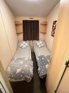 a small room with two beds and a window at Seawick Beach Caravan in Saint Osyth