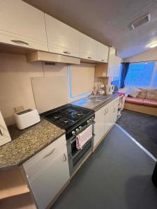 a small kitchen with a stove and a sink at Seawick Beach Caravan in Saint Osyth