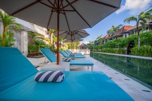 a row of blue lounge chairs next to a swimming pool at Sayang Sanur Duplex in Sanur