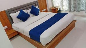 a bed with blue and white pillows in a room at Hotel Vinayak Naroda in Ahmedabad