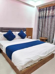 a bedroom with a large bed with blue pillows at Hotel Vinayak Naroda in Ahmedabad +10 photos