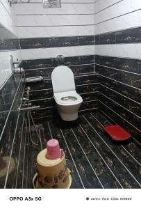 a bathroom with a toilet in a black tiled wall at Hotel Vinayak Naroda in Ahmedabad