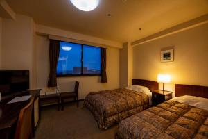 a hotel room with two beds and a desk and a window at ホテルグランフォーレ in Shikokuchuo +32 photos
